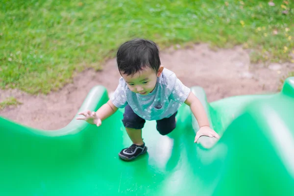 Liten asiatisk unge klättra uppför rutschbanan på lekplatsen i summ — Stockfoto