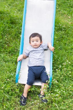 Küçük Asyalı çocuk slayt parkta oynarken
