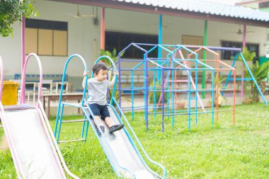 Küçük Asyalı çocuk slayt parkta oynarken
