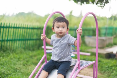 Küçük Asyalı Çocuk Bahçesi sunli altında slayt oynayan
