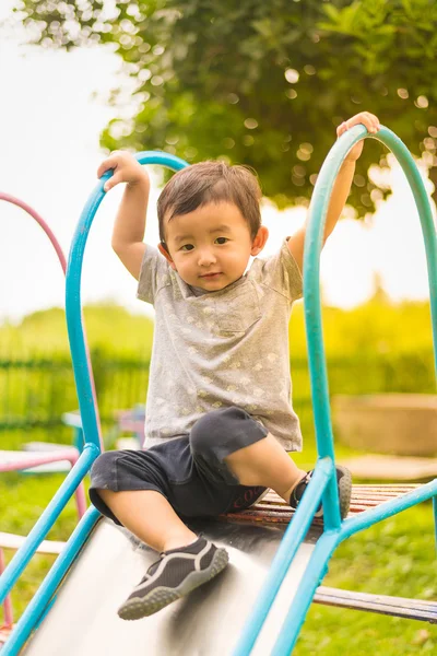 Pequeño asiático niño jugando diapositiva en el patio de recreo — Foto de Stock