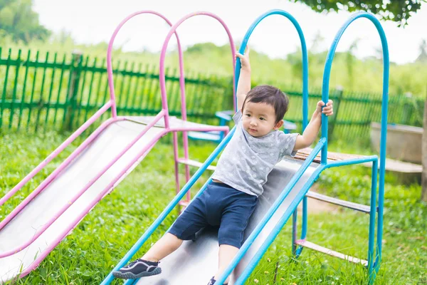 Pequeño asiático niño jugando diapositiva en el patio de recreo — Foto de Stock