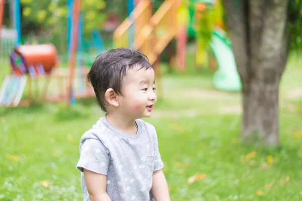 Little Asian kid playing and smiling at the playground under the — Stock Photo, Image