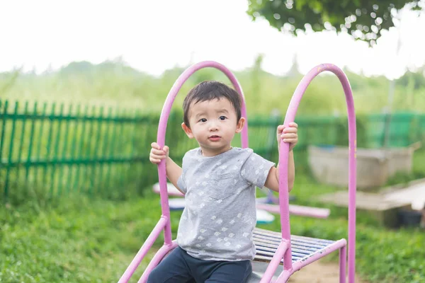 Pequeño niño asiático jugando diapositiva en el patio de recreo bajo el sunli — Foto de Stock