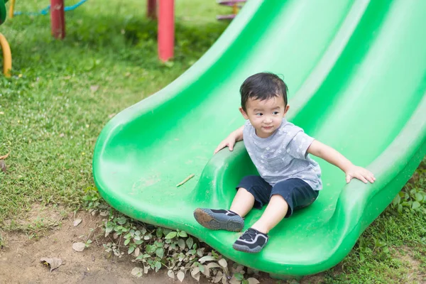 Pequeño asiático niño jugando diapositiva en el patio de recreo — Foto de Stock