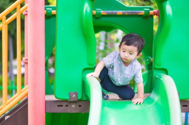 Küçük Asyalı çocuk slayt parkta oynarken