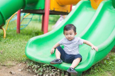 Küçük Asyalı çocuk slayt parkta oynarken