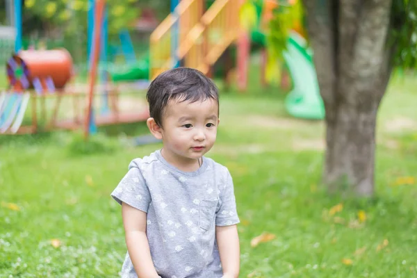 Pequeño niño asiático jugando y sonriendo en el patio de recreo bajo el — Foto de Stock