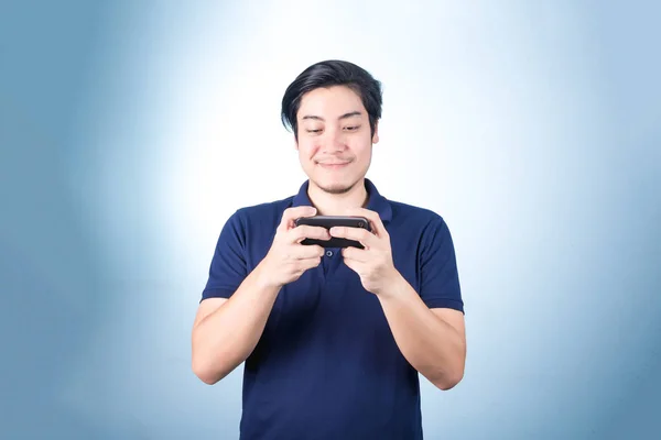 Chico asiático con teléfono móvil en la mano, sobre fondo azul — Foto de Stock
