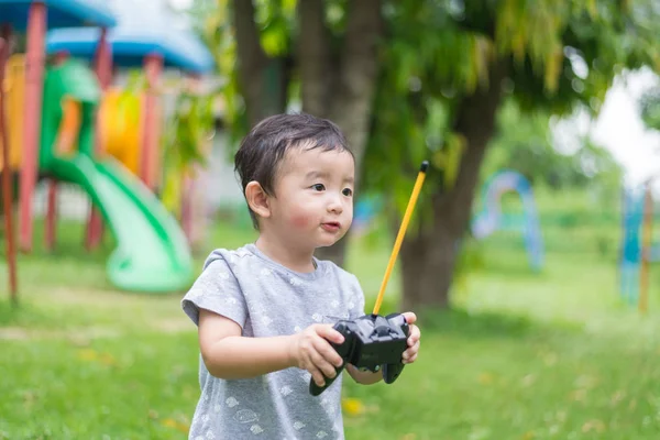 Pequeño niño asiático sosteniendo un control remoto de radio (control de han — Foto de Stock
