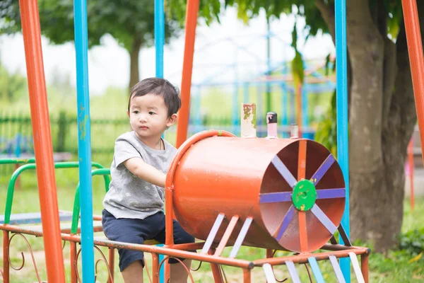 Genç Asyalı çocuk oyun bahçesi und sallanan bir demir tren