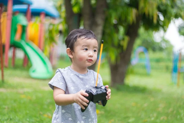 Pequeño niño asiático sosteniendo un control remoto de radio (control de han — Foto de Stock