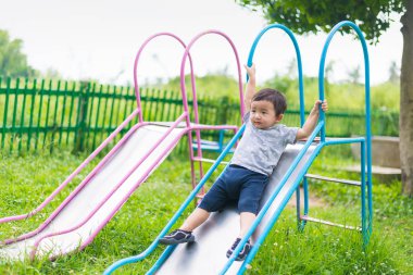 Küçük Asyalı çocuk slayt parkta oynarken