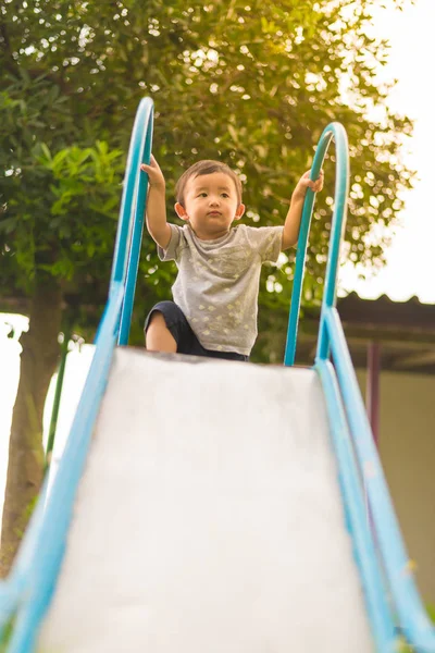 Pequeño asiático niño jugando diapositiva en el patio de recreo — Foto de Stock