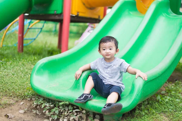 Pequeño asiático niño jugando diapositiva en el patio de recreo — Foto de Stock