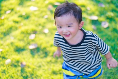 Küçük Asyalı çocuk oyun ve Bahçesi altında gülüp