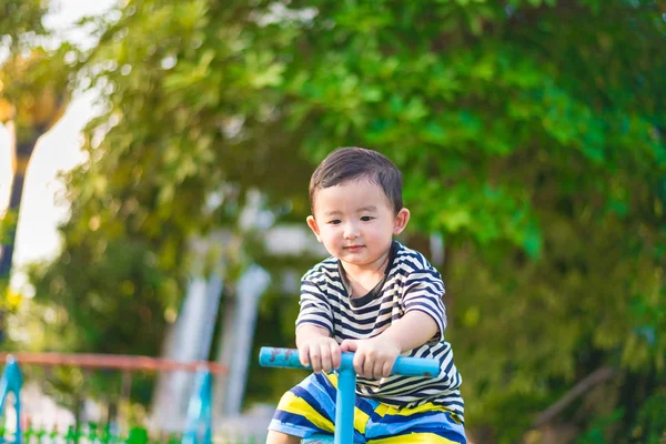 Азиатский ребенок катается на качелях на детской площадке — стоковое фото