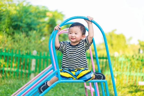 Pequeño asiático niño jugando diapositiva en el patio de recreo — Foto de Stock