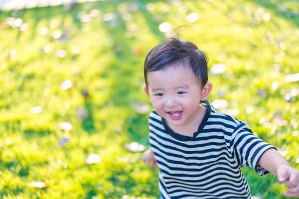 Pequeno garoto asiático brincando e sorrindo no playground sob o — Fotografia de Stock