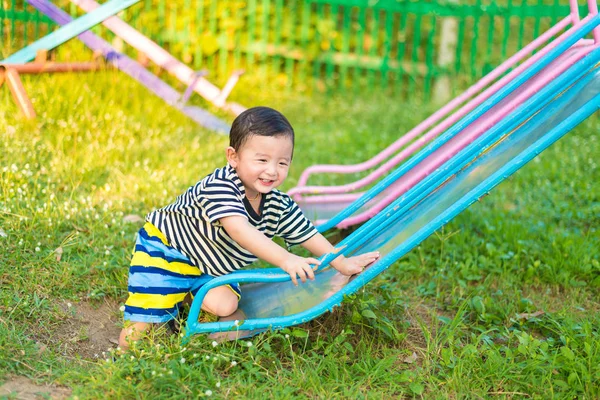 Kleine Aziatische jongen dia spelen op de speelplaats — Stockfoto