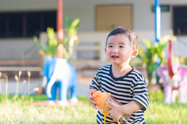 Asiatiska baby pojke drink med vattenflaska vid lekplats utomhus, — Stockfoto