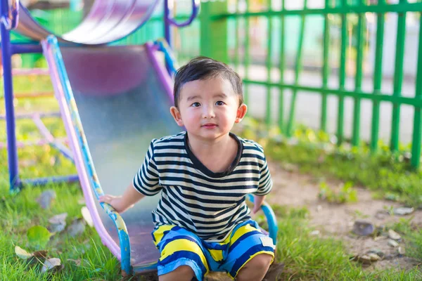 Pequeño asiático niño jugando diapositiva en el patio de recreo — Foto de Stock