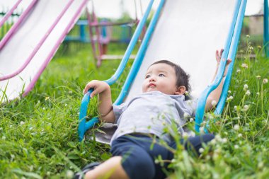 Küçük Asyalı çocuk slayt parkta oynarken