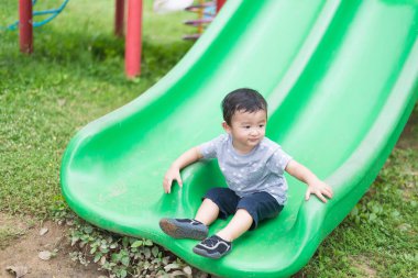 Küçük Asyalı çocuk slayt parkta oynarken