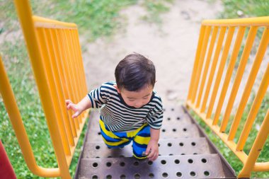 Asyalı çocuk parkta merdivenlerden yukarı gider. büyümenin kavramı.