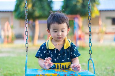 Genç Asyalı çocuk oyun bahçesi altında sallanan bir demir