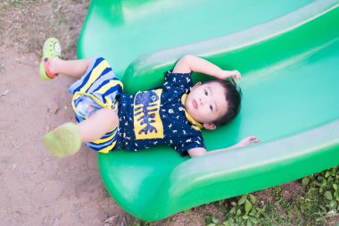 Küçük Asyalı çocuk slayt parkta oynarken.