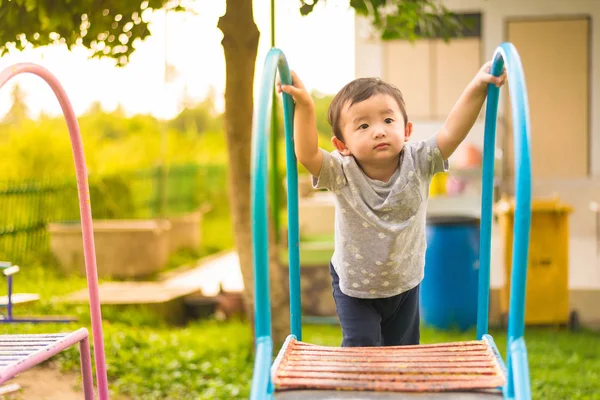 Pequeño asiático niño jugando diapositiva en el patio de recreo — Foto de Stock