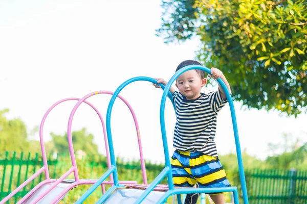 Pequeño asiático niño jugando diapositiva en el patio de recreo — Foto de Stock