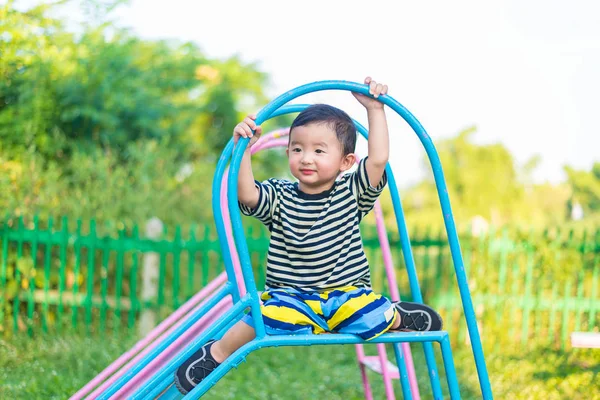 Pequeño asiático niño jugando diapositiva en el patio de recreo — Foto de Stock