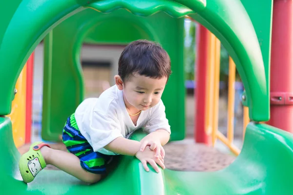 Little Asian kid playing slide at the playground under the sunli — Stock Photo, Image