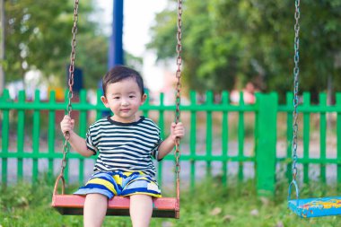 Genç Asyalı çocuk oyun bahçesi altında sallanan bir demir