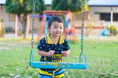 Genç Asyalı çocuk oyun bahçesi altında sallanan bir demir