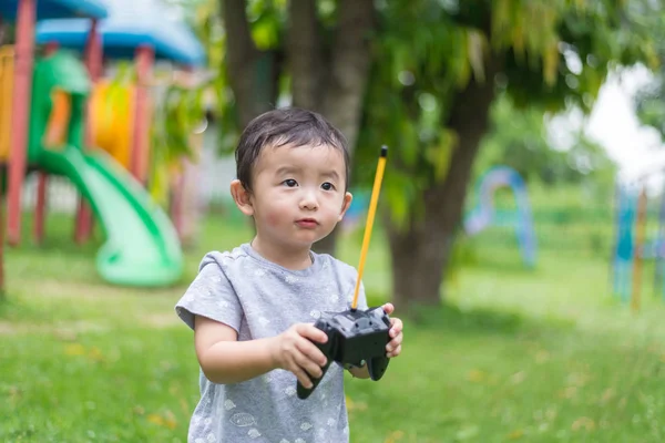 Little Asian kid holding a radio remote control (controlling han — Stock Photo, Image