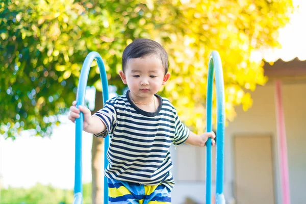 Liten asiatisk unge spelar slide på lekplatsen — Stockfoto