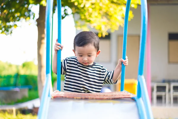 Pequeño asiático niño jugando diapositiva en el patio de recreo — Foto de Stock