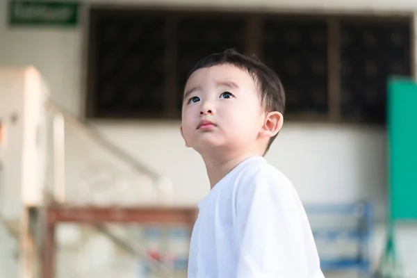 Primer plano pequeño chico asiático mirando hacia arriba en algún lugar y pensando con — Foto de Stock