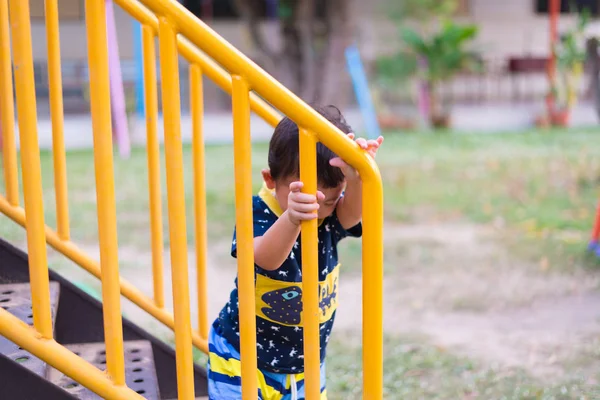 Asyalı çocuk parkta merdivenlerden yukarı gider.