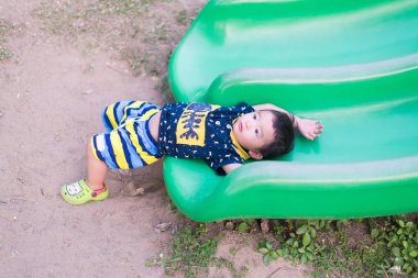 Küçük Asyalı çocuk slayt parkta oynarken.