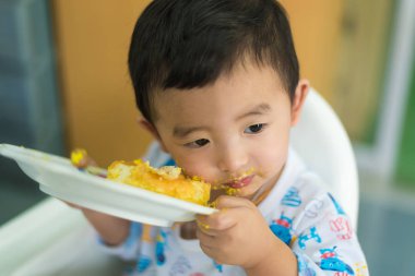Asyalı çocuk yüzünde doğum günü pastası ile krem yeme.