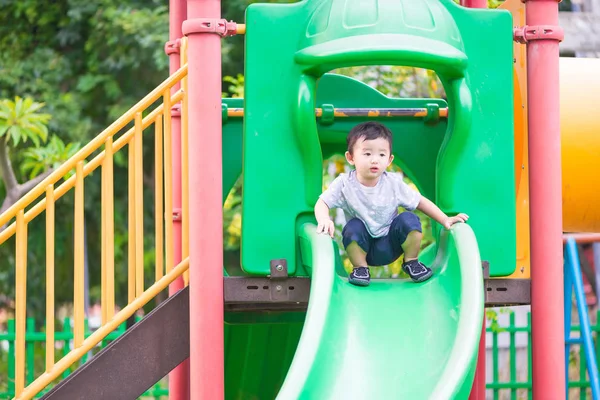 Pequeño asiático niño jugando diapositiva en el patio de recreo — Foto de Stock