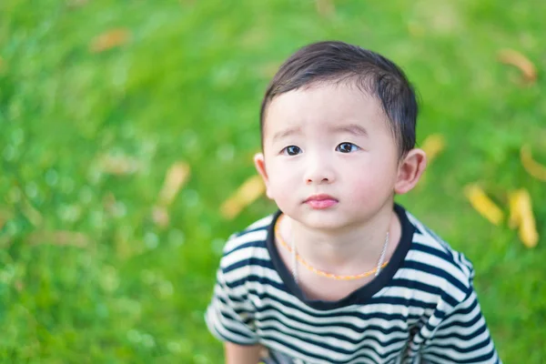 Primer plano pequeño chico asiático mirando hacia arriba en algún lugar y pensando con — Foto de Stock