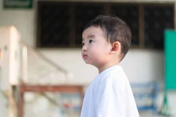 Маленький азиатский мальчик крупным планом смотрит вверх и думает: — стоковое фото