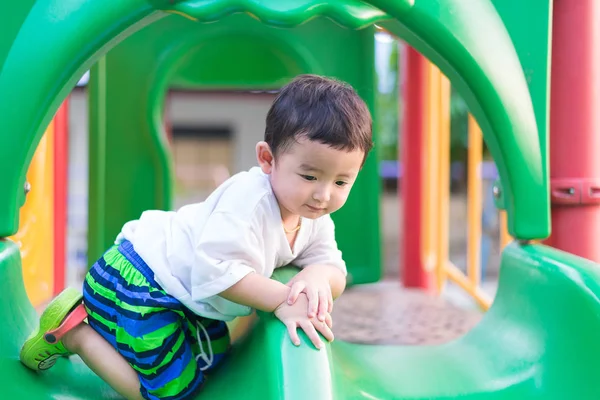 Pequeño niño asiático jugando diapositiva en el patio de recreo bajo el sunli — Foto de Stock