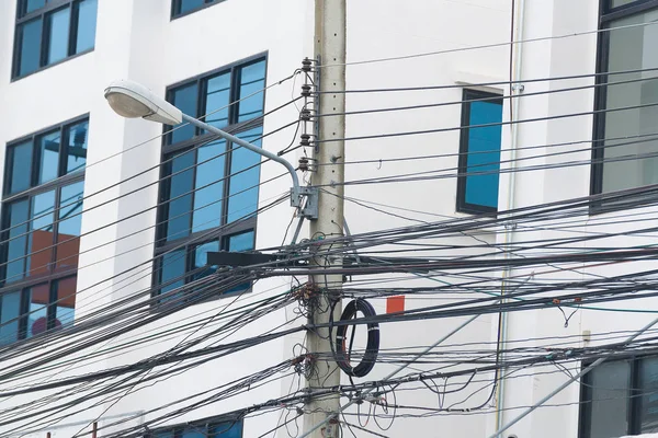 Poste de alta tensión con cables enredados en el edificio detrás . — Foto de Stock