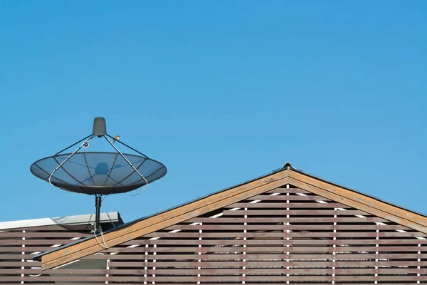 Grote zwarte satellietschotel op het dak met blauwe lucht. — Stockfoto